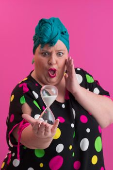 Portrait of plus size young lady smiling hands holds sand clock isolated on pink color background. High quality photo