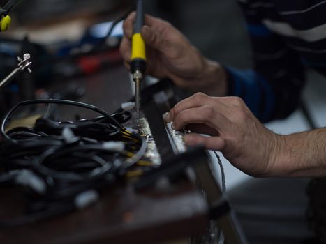 Industrial worker man soldering cables of manufacturing equipment in a factory. Selective focus. High quality photo