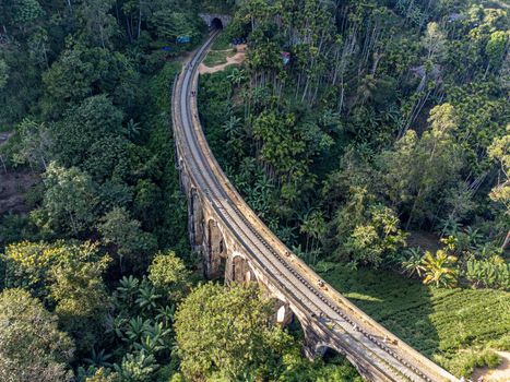 Sri Lanka. The attraction is the ancient railway Nine-arch Demodara Bridge in the midst of a dense tropical forest. Shooting from the air on a drone. Sunny day, sunset.