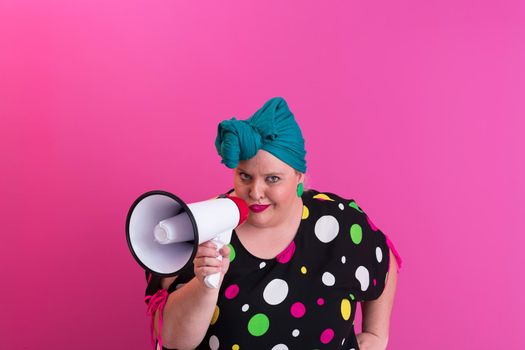 Funny plus size woman woman girl posing isolated on pastel pink wall background studio portrait. People sincere emotions lifestyle concept. Mock up copy space. Screaming in megaphone. High quality photo