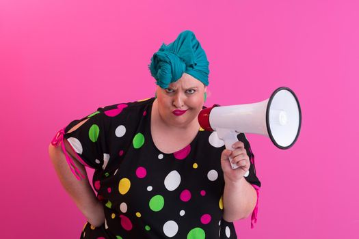 Funny plus size woman woman girl posing isolated on pastel pink wall background studio portrait. People sincere emotions lifestyle concept. Mock up copy space. Screaming in megaphone. High quality photo