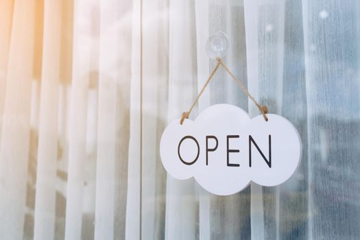 A business sign that says Open on cafe or restaurant hang on door at entrance. Vintage color tone style.