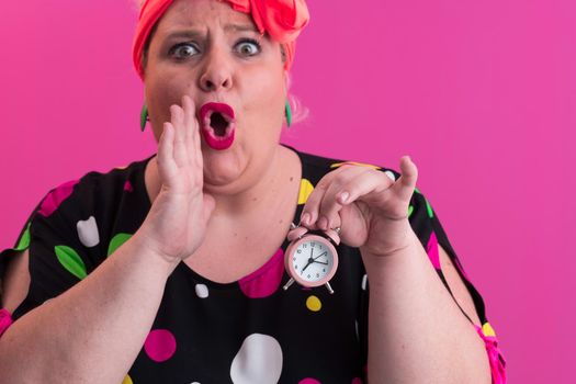 Portrait of plus size young lady smiling hands holds sand clock isolated on pink color background. High quality photo