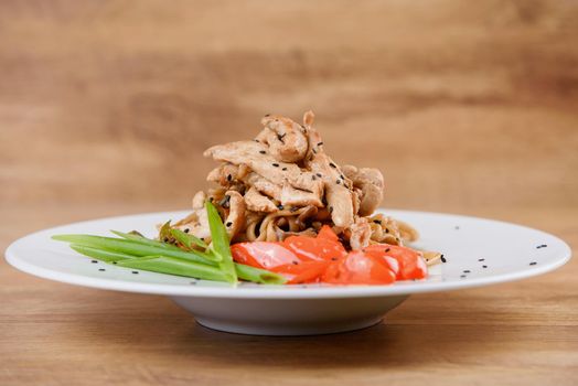 Noodles with meat and vegetables on a white plate