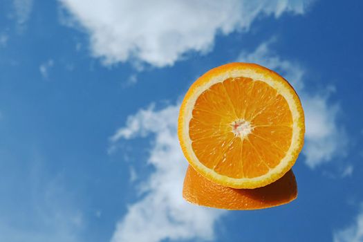 Orange citrus fruit tropical orange on blue sky and clouds background. Orange in the mirror surreal minimal concept.