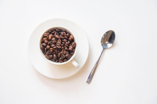 white cup and coffee beans on a white background. Selective focus.