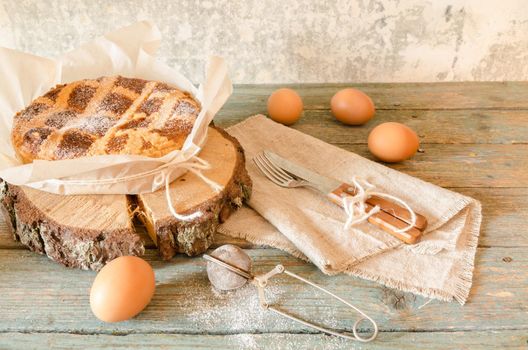 Neapolitan Easter cake with ricotta and wheat on old wooden table. Next egg, knife and fork. Rustic style.