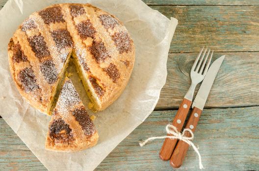 Neapolitan pie on wrapping paper. Next knife and fork. Rustic style.