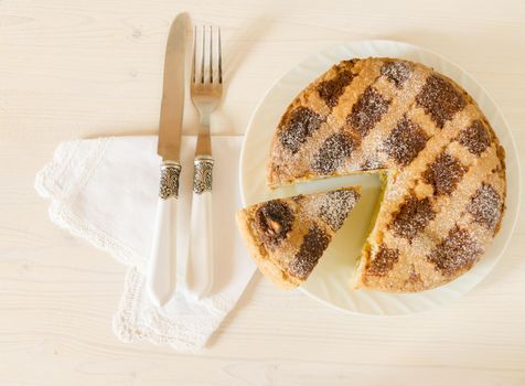 Neapolitan Easter cake with ricotta and wheat on white wooden table. Next egg, knife and fork. Rustic style.