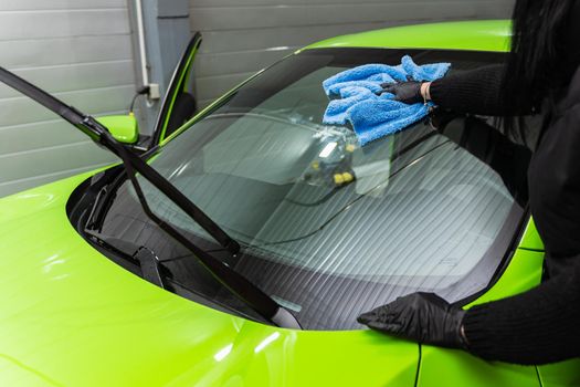 Polishing the car glass with a blue microfiber cloth.