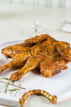 Tobacco chicken on a white plate with a glass of red wine, cutlery. Grilled chicken.