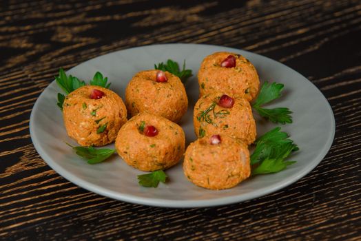 Carrot pkhali decorated with parsley and pomegranate. Georgian appetizer on a gray plate on a dark wooden table.