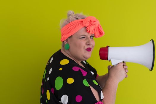 Funny plus size woman woman posing isolated on pastel green background studio portrait. People emotions lifestyle concept. Mock up copy space. Screaming in megaphone. High quality photo