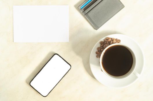 A cup of coffee with coffee beans, mobile phone with mock up, bank cards and empty blank on the table.Business concept.Top view,flatlay.