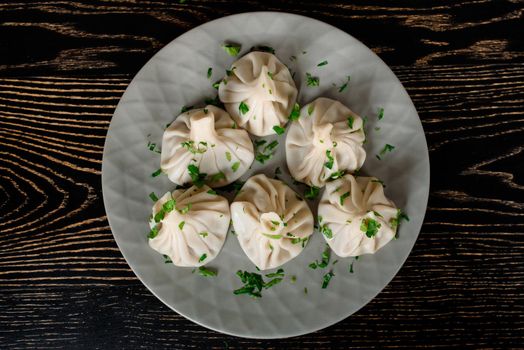 Khinkali traditional Georgian cuisine decorated with cilantro on a gray plate. Top view