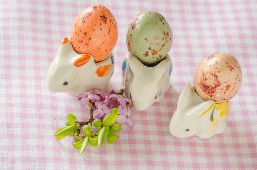 Three porcelain rabbit with eggs and small bouquet of beautiful flowers. Easter still life.