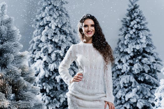 New year celebration.Happy girl with falling snow. Young woman weared in a warm white pullover and white socks. Winter holidays in snowy day