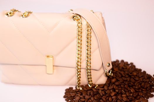 fashion beige leather woman handbag with gold chain with coffee beans nearby isolated on white background. Product photography. bags and purses for women.