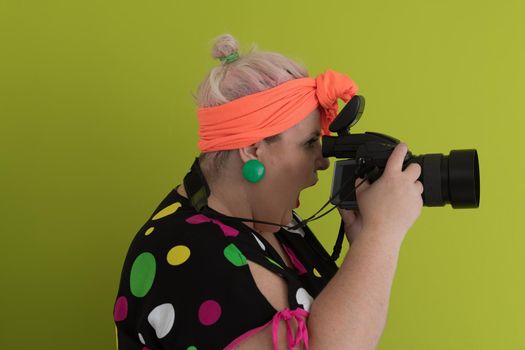 plus size smiling woman with funny emotional face expression with vintage camera in dress isolated on green background, traveler on vacation, summer fashion style, excited tourist. High quality photo