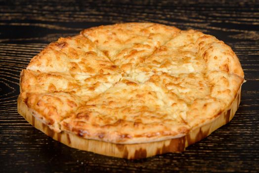Tortilla baked with cheese on a wooden plate on a dark wooden table. Cheese pastries with a crispy crust.
