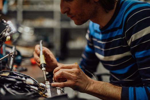 Industrial worker man soldering cables of manufacturing equipment in a factory. Selective focus. High-quality photo
