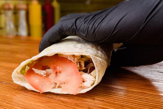 Burrito making process. The chef wraps stuffed pita on a wooden table. Mexican dish.