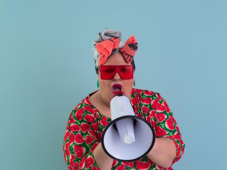 Funny plus size woman posing isolated on cyan background studio portrait. Screaming in a megaphone. People emotions lifestyle concept. Mock up copy space. High quality photo