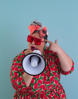 Funny plus size woman posing isolated on cyan background studio portrait. Screaming in a megaphone. People emotions lifestyle concept. Mock up copy space. High quality photo