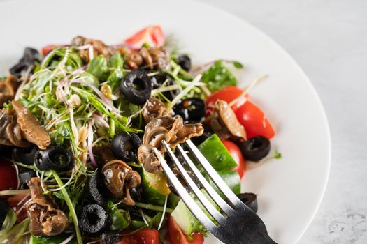 Green salad with escargot grape snails on white background. French gourmet cuisine