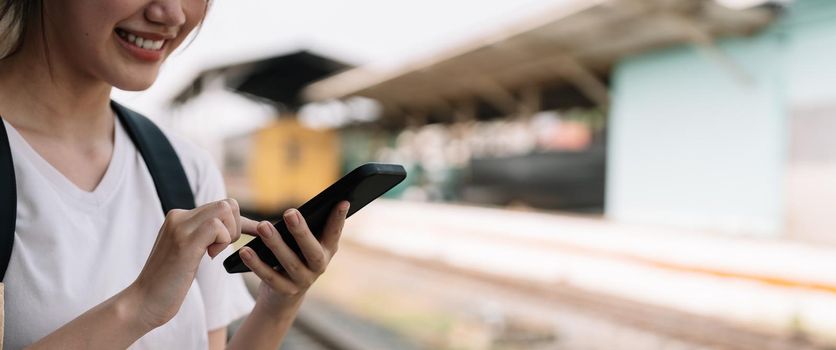 Close up hand of woman using smartphone at train station summer travel concept.