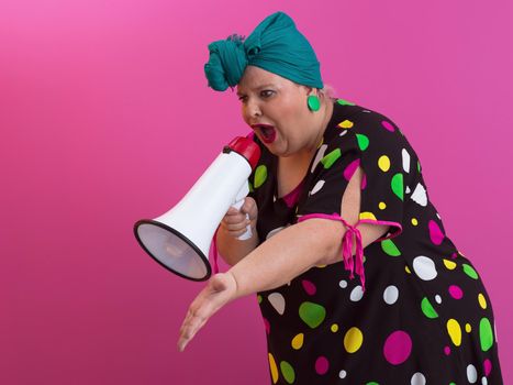 Funny plus size woman woman posing isolated on pink background studio portrait. People emotions lifestyle concept. Mock up copy space. Screaming in megaphone. High quality photo