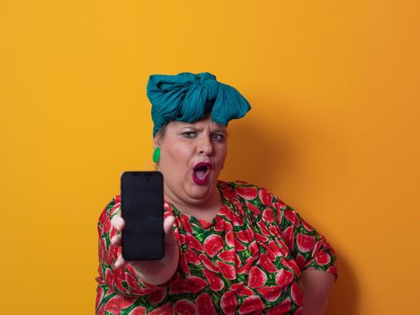 Trendy plus size woman having conversation talking by smartphone over yellow background smiling with an idea or question pointing finger with happy face, number one. High quality photo