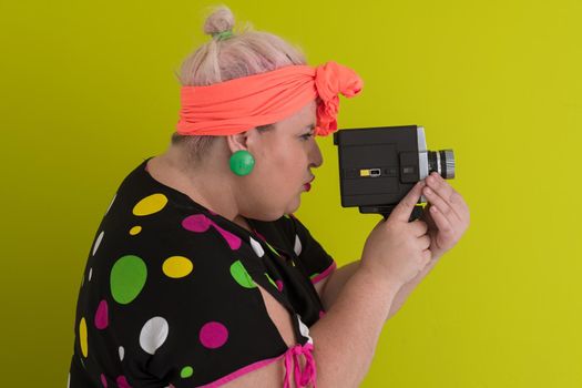 plus size smiling woman with funny emotional face expression with vintage camera in dress isolated on green background, traveler on vacation, summer fashion style, excited tourist. High quality photo