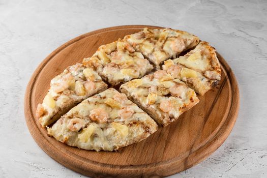 Pinsa romana with shrimps and pineapple on wooden plate on white background. Seafood scrocchiarella