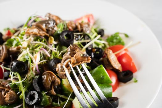 Green salad with escargot grape snails on white background. French gourmet cuisine