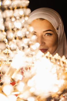 Fashion muslim model near big expensive chandelier. Islamic religion