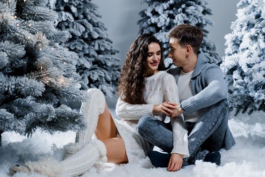 New year love story. Couple kiss and hug. Happy young couple near christmas trees in winter day.