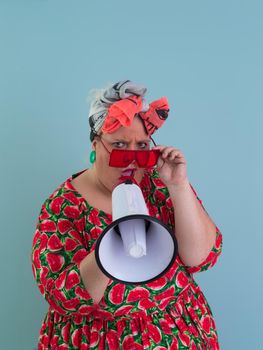 Funny plus size woman posing isolated on cyan background studio portrait. Screaming in a megaphone. People emotions lifestyle concept. Mock up copy space. High quality photo
