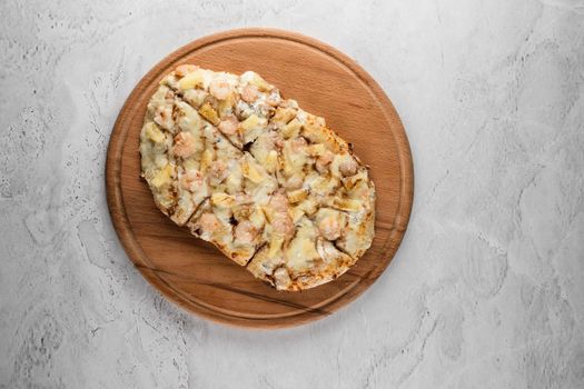 Pinsa romana with shrimps and pineapple on wooden plate on white background. Seafood scrocchiarella