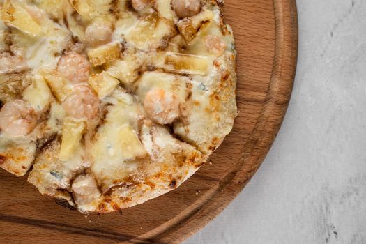 Pinsa romana with shrimps and pineapple on wooden plate on white background. Seafood scrocchiarella