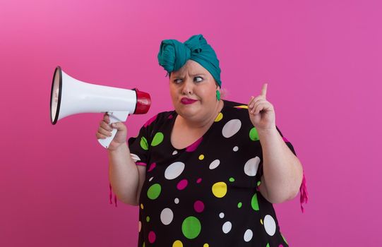 Funny plus size woman woman posing isolated on pink background studio portrait. People emotions lifestyle concept. Mock up copy space. Screaming in megaphone. High quality photo