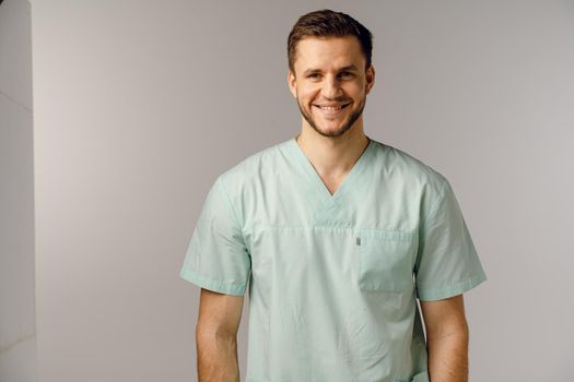 Surgeon weared in medical robe smile and posing on white background. Handsome happy doctor posing in studio