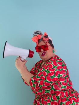 Funny plus size woman posing isolated on cyan background studio portrait. Screaming in a megaphone. People emotions lifestyle concept. Mock up copy space. High quality photo