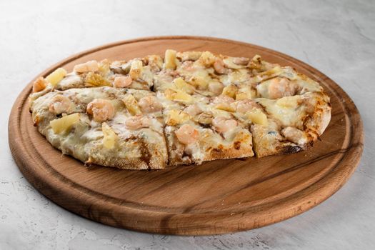 Pinsa romana with shrimps and pineapple on wooden plate on white background. Seafood scrocchiarella