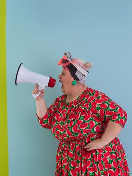 Funny plus size woman posing isolated on cyan background studio portrait. Screaming in a megaphone. People emotions lifestyle concept. Mock up copy space. High quality photo