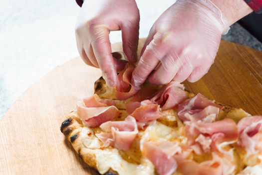 Chef cooking pinsa romana with pear, cheese, prosciutto in delivery box. Scrocchiarella gourmet italian cuisine