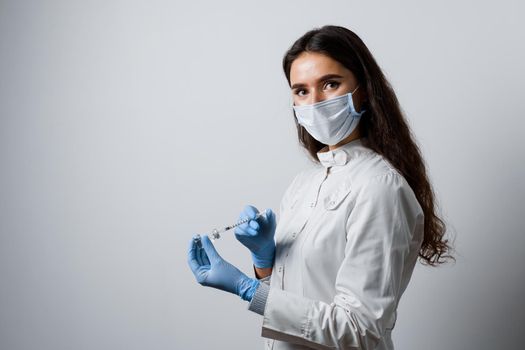 Doctor holding syringe with coronavirus vaccine. Covid-19 Vaccination. Stop quarantine. Attractive girl in medical gloves with syringe and medication