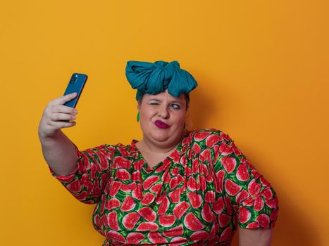 Trendy plus size woman taking selfie photo by smartphone over yellow Fortuna gold background smiling with an idea or question pointing finger with a happy face. High quality photo