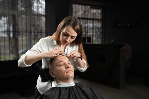 Straight razor cut man hair in barbershop. Attractive woman barber making hairstyle for handsome man