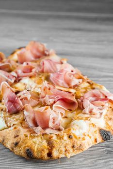 Scrocchiarella with pear, cheese, prosciutto on grey wooden background. Pinsa romana gourmet italian cuisine. Junk food.